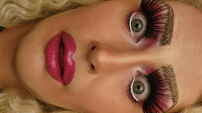 Drag Queen mit dramatischem Make-up, langen Wimpern und überraschtem Gesichtsausdruck